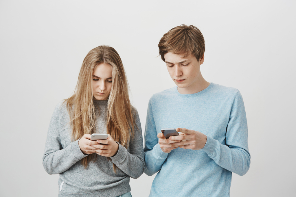 two-young-people-using-smartphone-girl-guy-texting-with-serious-faces.jpg